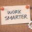 Zettel mit Work smarter auf einer Holzwand, bezogen auf die Effizienz Steigerung