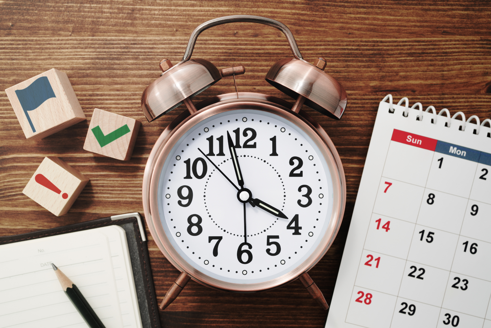 Bild mit Wecker und Kalender sowie einem Block und Stift als Sinnbild für Zeitmanagement