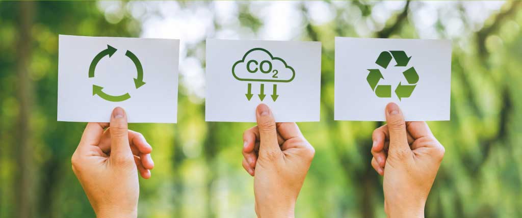 Drei Hände halten die Zeichen der Nachhaltigkeit nach oben (Recycling, CO2)